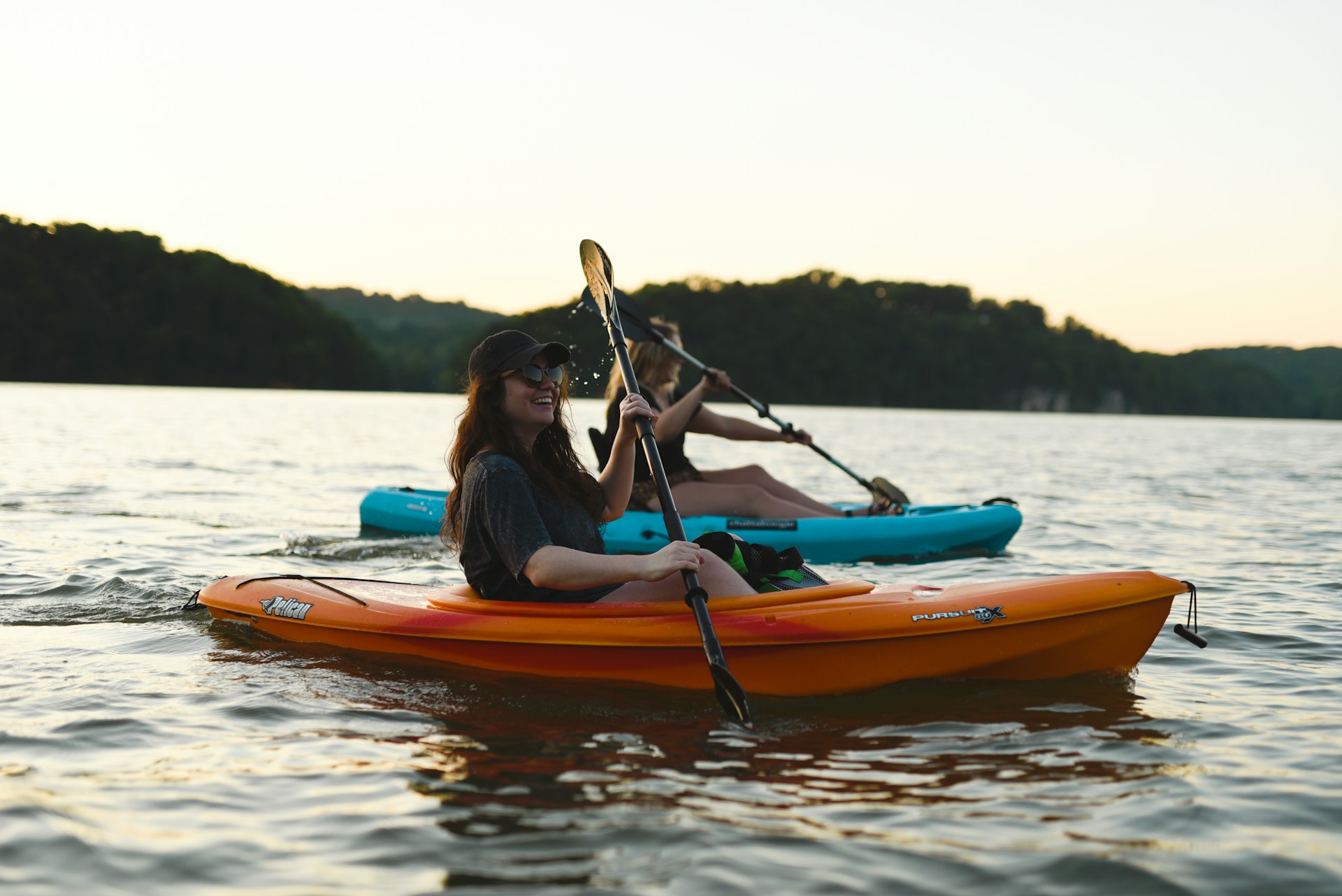 Woman in blue shirt and blue denim jeans riding orange kayak on water during daytime